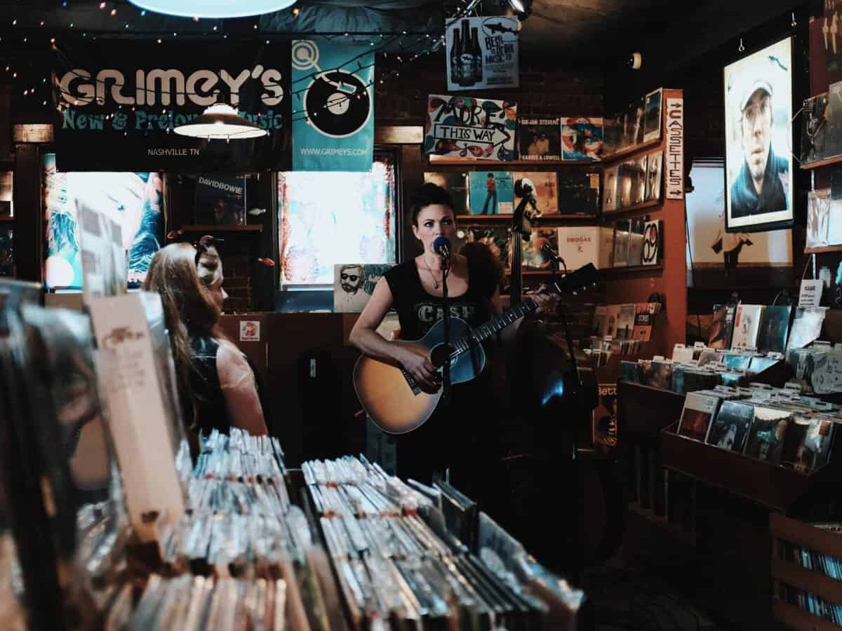 A musician in a record shop is playing her Guitar