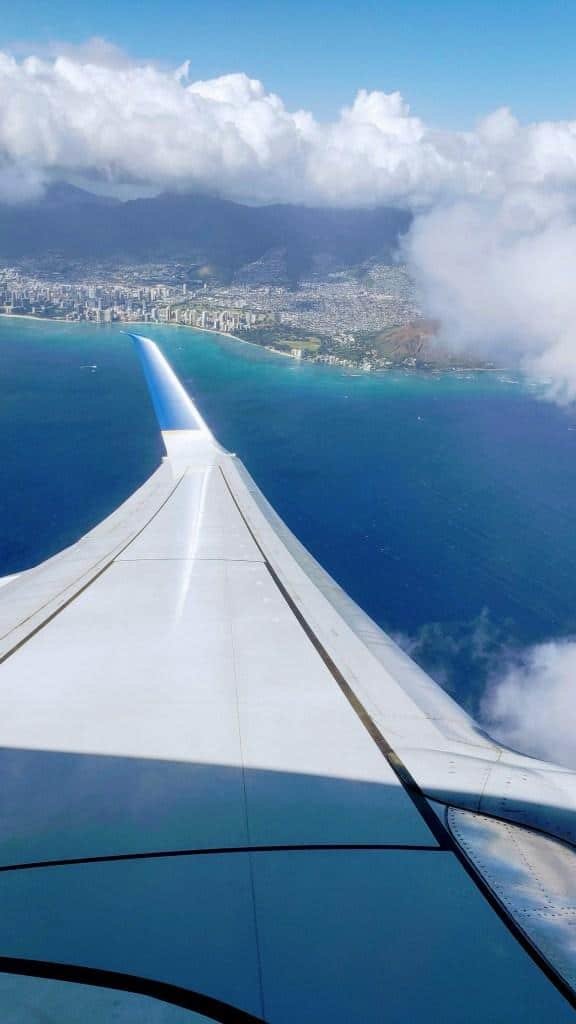 Una toma desde arriba del ala de un avión acercándose a una isla.