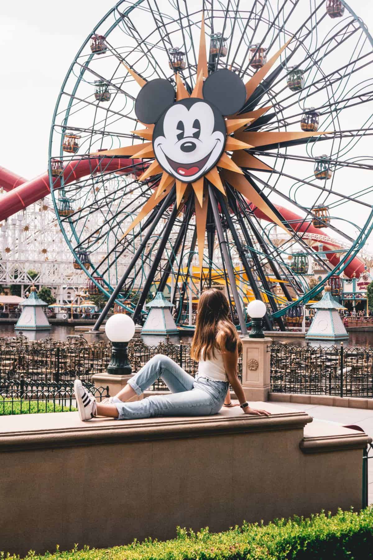 A girl posing in front of the Mickey Mouse Ferris Wheel in Disneyland California.