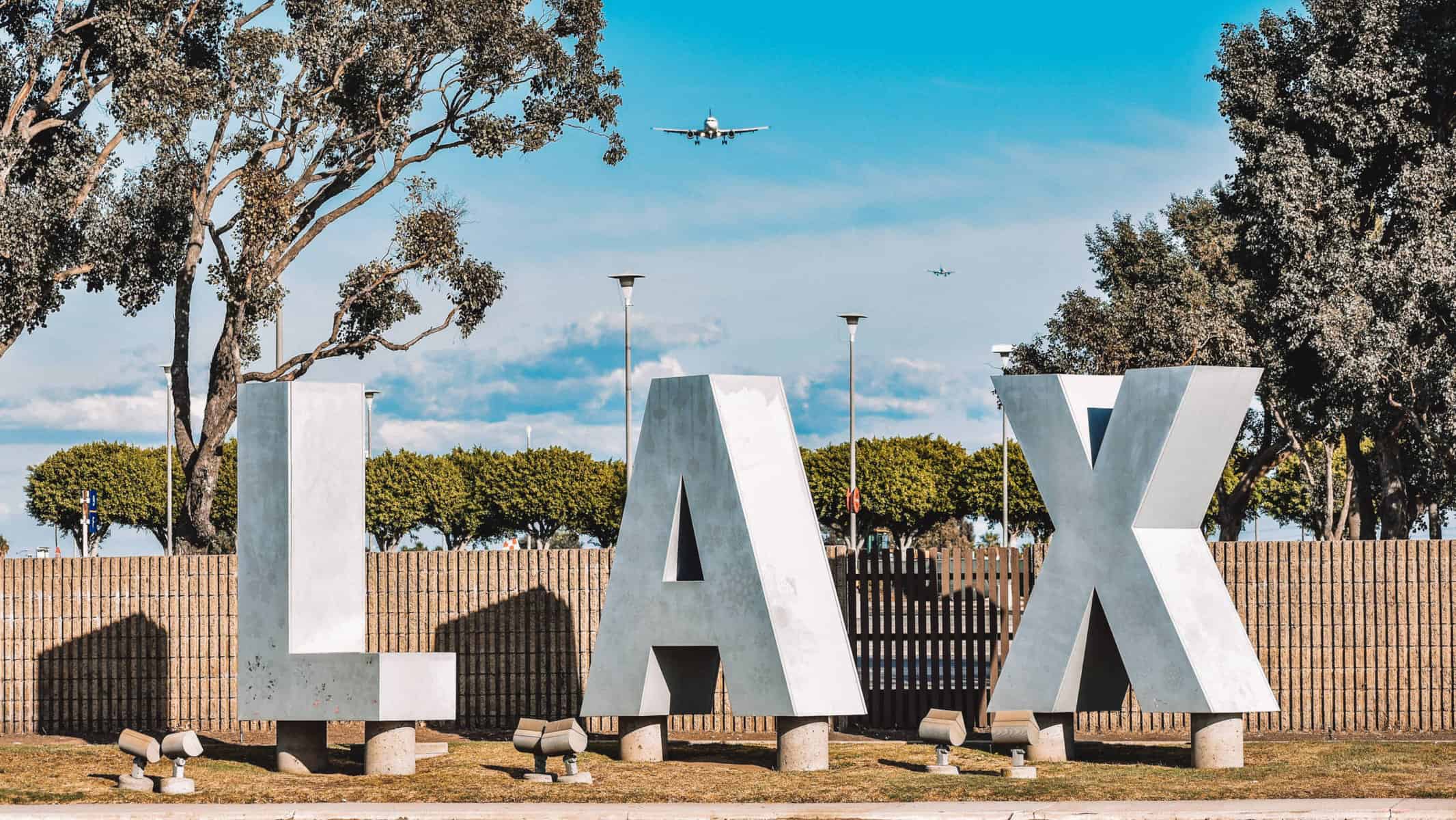 A shot of an aircraft taking off right over the LAX sign!