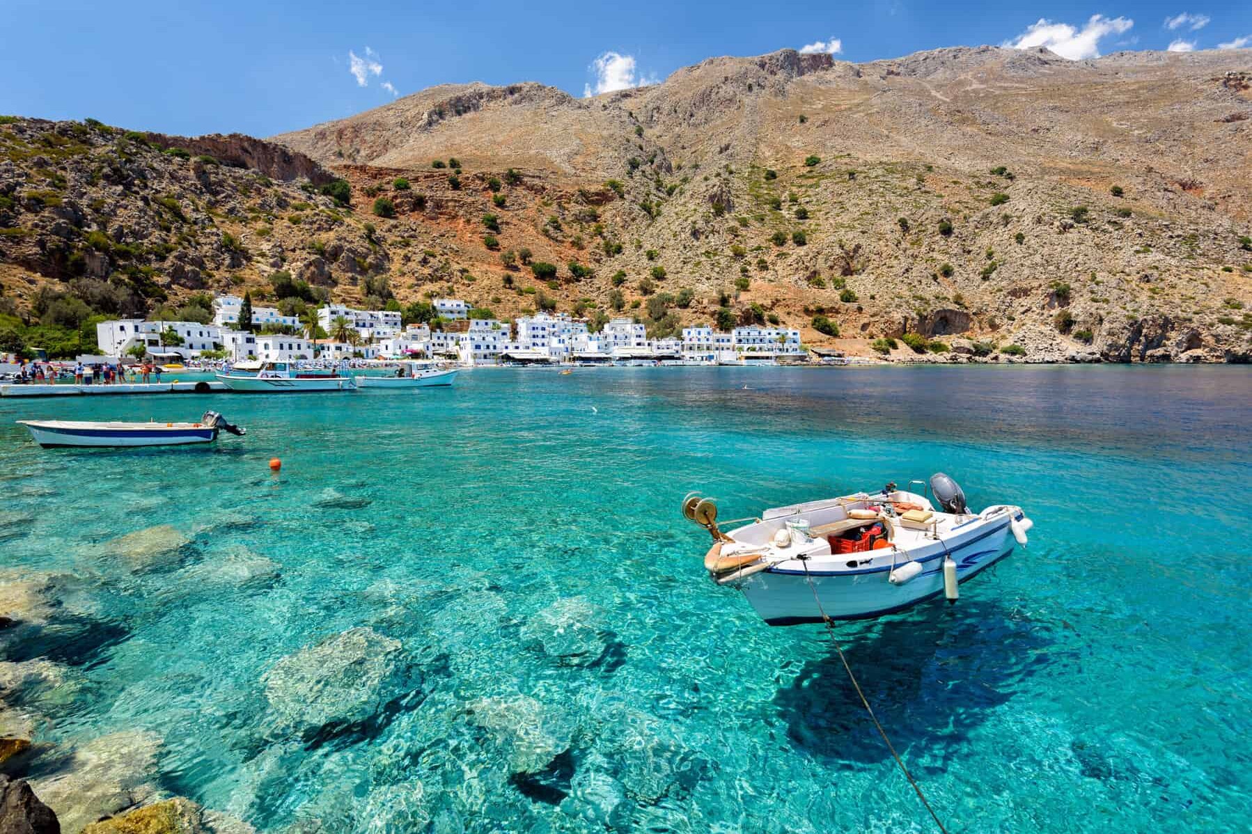 Petit bateau à moteur dans la baie aux eaux claires de la ville de Loutro sur l'île de Crète