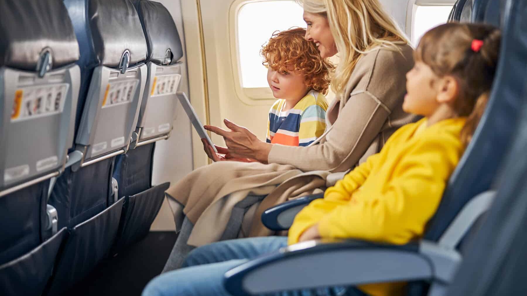 Niños dentro de un avión mostrando una tableta a un niño.