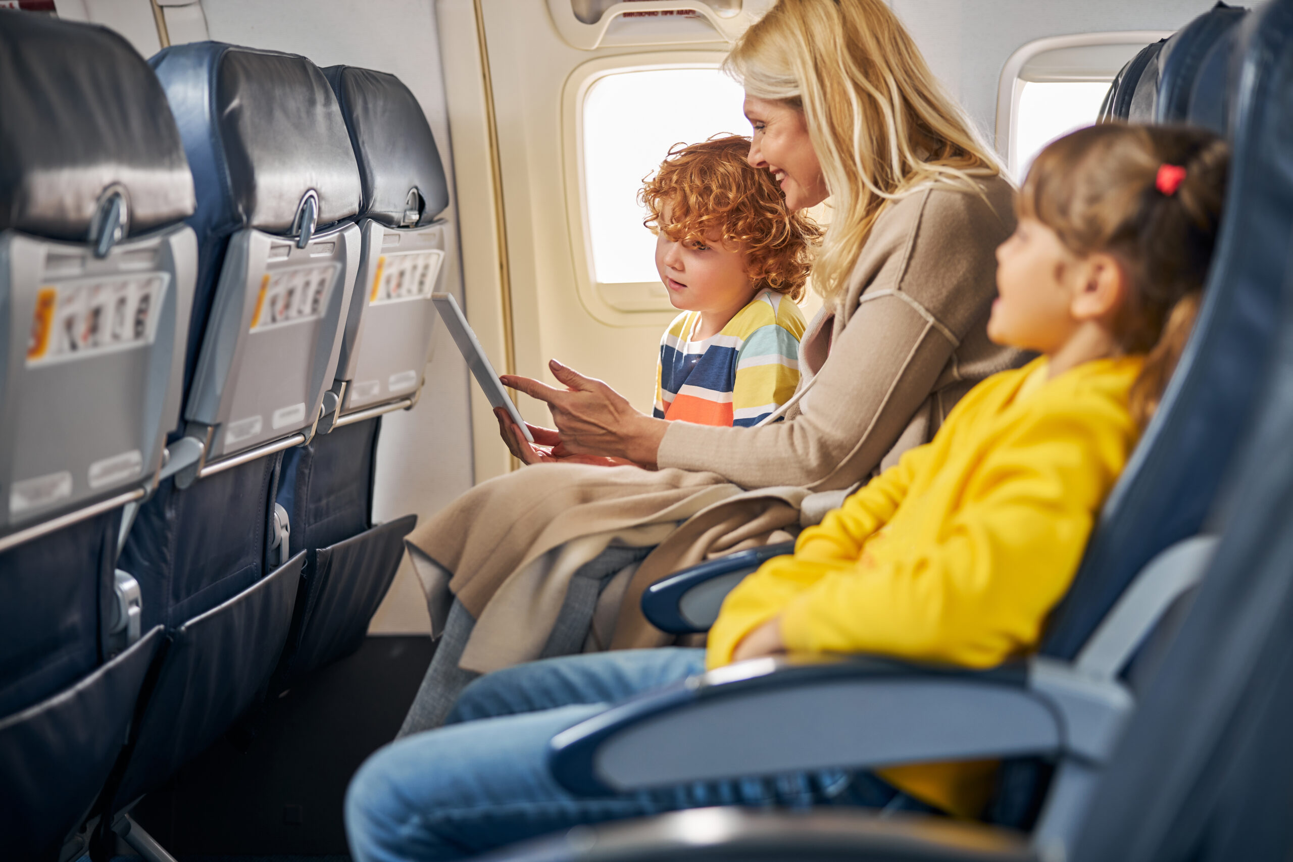 Niños dentro de un avión mostrando una tableta a un niño.